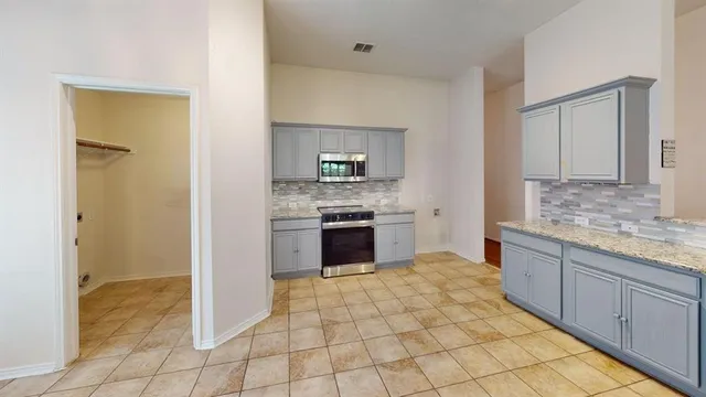 a large kitchen with granite countertop a stove a sink and a refrigerator