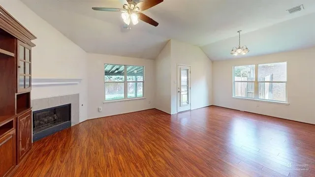 a view of an empty room with wooden floor fireplace and a window