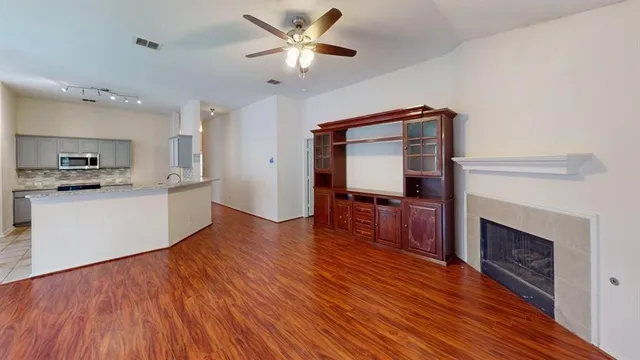 a living room with stainless steel appliances kitchen island a fireplace and wooden floor