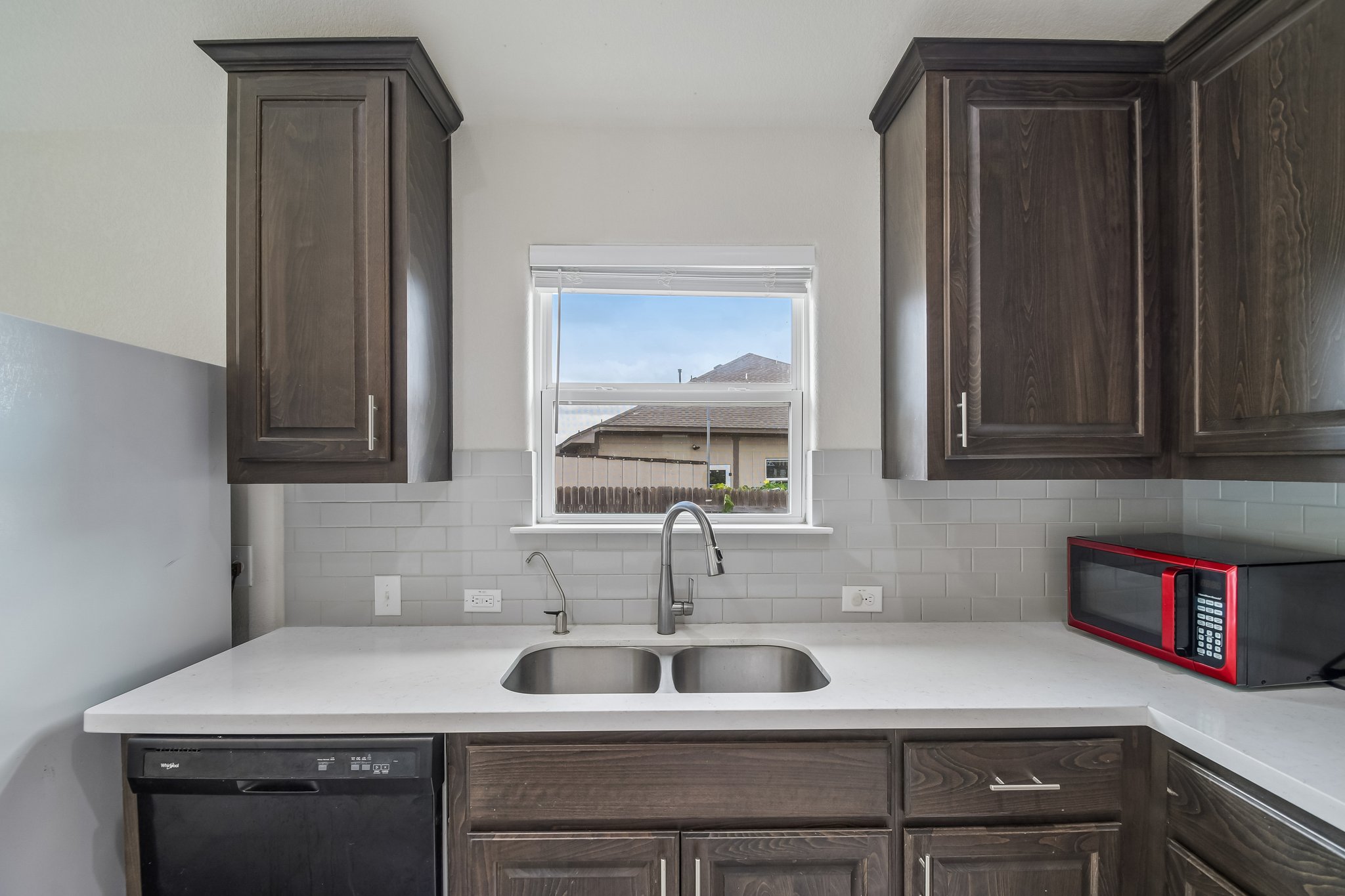 280 Rimrock Court Bastrop, TX 78602 - Photo 10 of 34 Rich dark wood cabinetry pairs with clean stone counters surrounding a double basin sink.