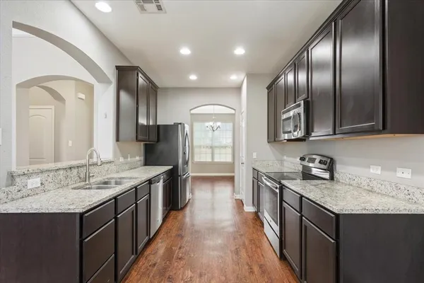 a large kitchen with stainless steel appliances granite countertop a lot of counter space and wooden floors