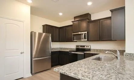 a kitchen with stainless steel appliances granite countertop a refrigerator stove microwave and sink