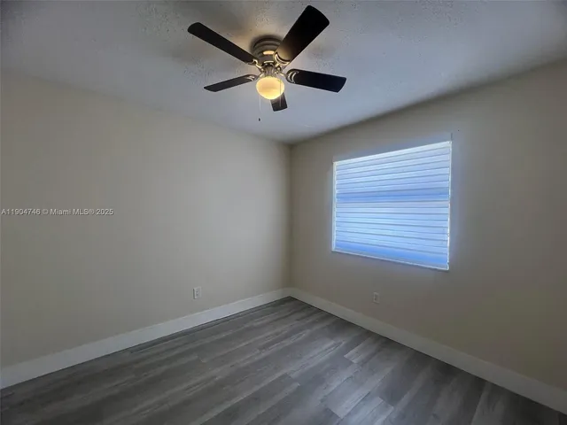 an empty room with wooden floor and ceiling fan