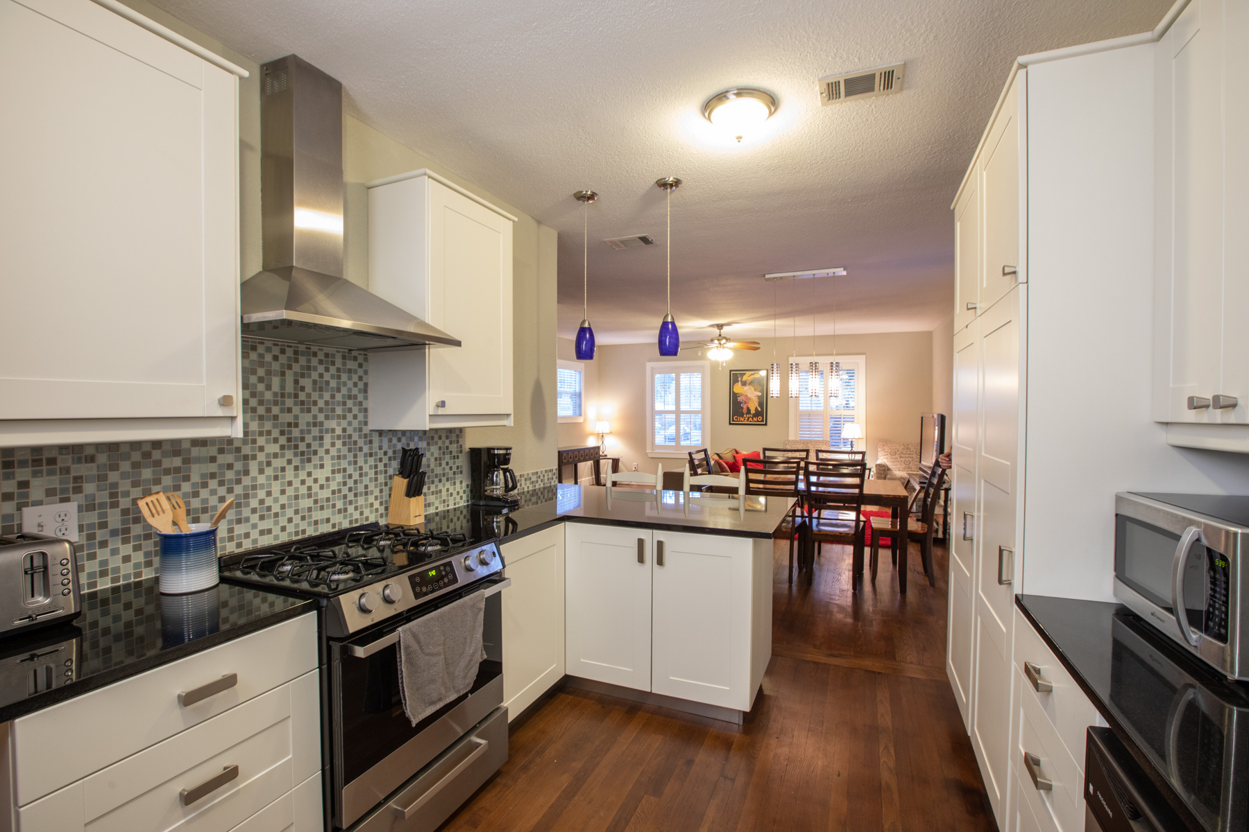 702 West N Loop Boulevard Austin, TX 78751 - Photo 11 of 23 Culinary delights await in this modern kitchen with granite counters and rich hardwood flooring, seamlessly flowing into the living area.