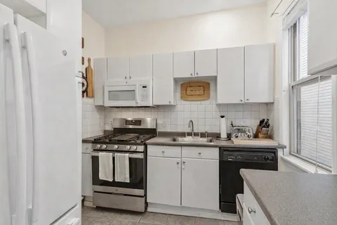 a kitchen with stainless steel appliances granite countertop white cabinets sink and stove