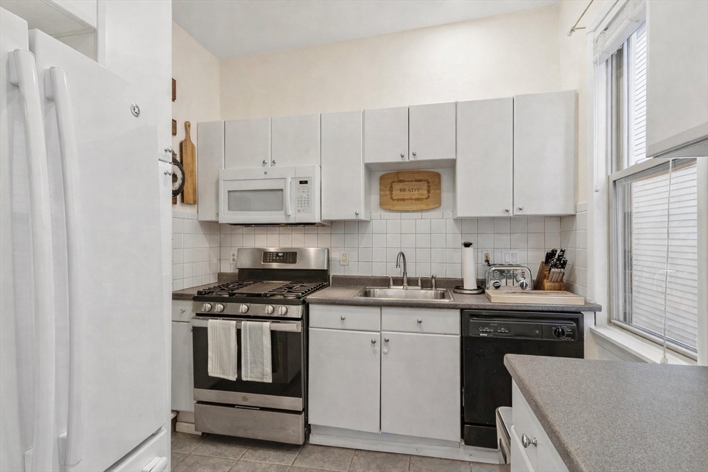787 East 3rd Street, Unit 2 Boston, MA 02127 - Photo 7 of 15 a kitchen with stainless steel appliances granite countertop white cabinets sink and stove