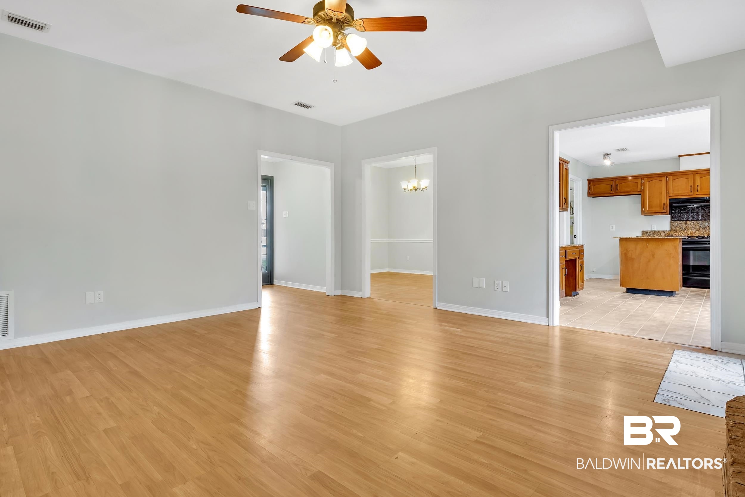 6616 Conde Court Mobile, AL 36695 - Photo 8 of 27 Unfurnished living room featuring visible vents, ceiling fan with notable chandelier, baseboards, and light wood-style floors