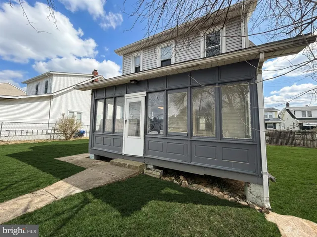 a view of a house with a small yard and a large tree with wooden fence
