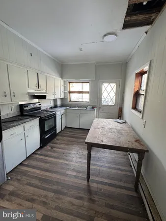 a kitchen with cabinets wooden floor and stainless steel appliances