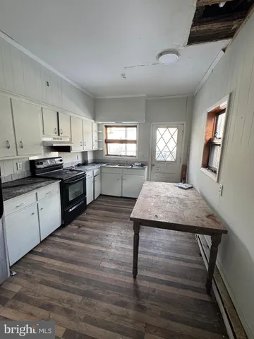 a kitchen with cabinets wooden floor and stainless steel appliances