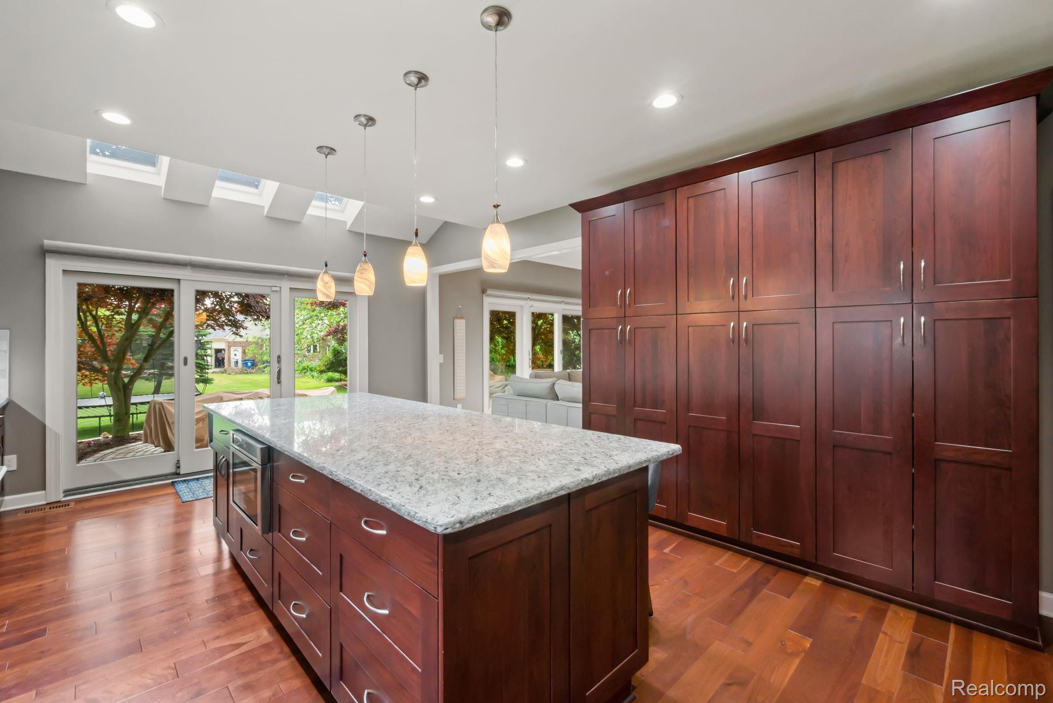1902 Grayslake Drive Rochester, MI 48306 - Photo 17 of 76 Kitchen featuring a large central island with a light-toned countertop, extensive built-in dark wood cabinetry, wood-finish flooring, recessed lighting, and multiple skylights