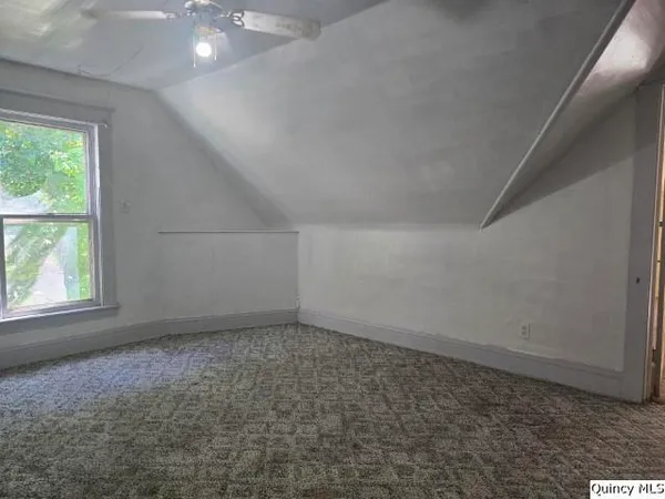 an empty room with chandelier fan