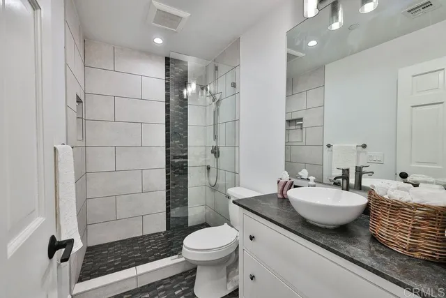 a bathroom with a granite countertop sink toilet a mirror and shower