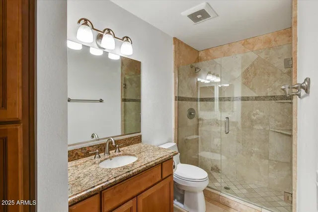 a bathroom with a granite countertop sink toilet and shower