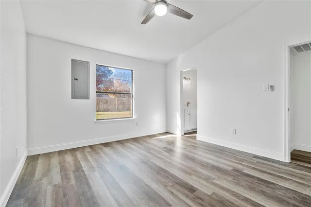 an empty room with wooden floor chandelier fan and windows