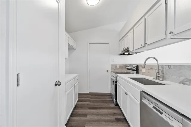 a kitchen with white cabinets and sink