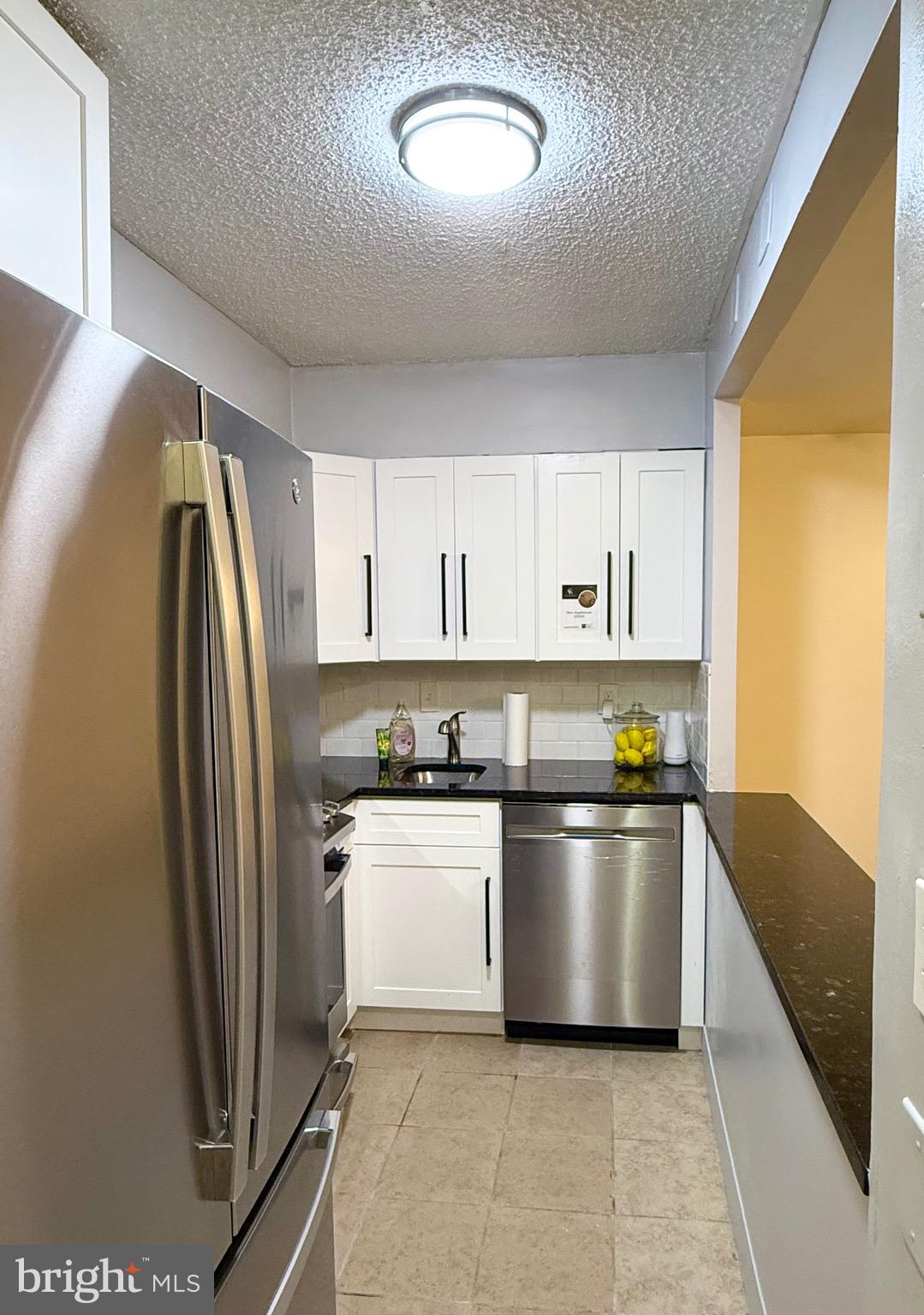 1245 13th Street Northwest, Unit 109 Washington, DC 20005 - Photo 9 of 25 a kitchen with stainless steel appliances granite countertop a refrigerator a sink a stove and white cabinets