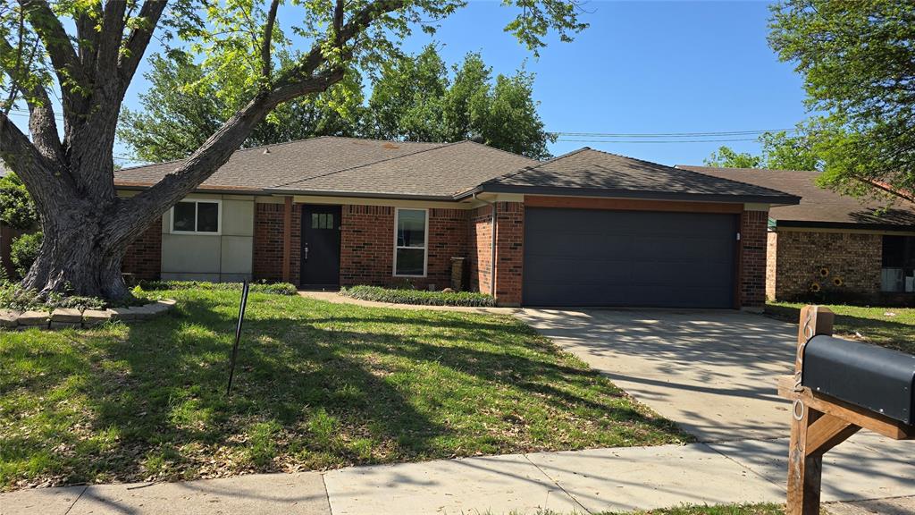 6020 Birchhill Road Watauga, TX 76148 - Photo 1 of 1 Single story home featuring a front yard, a garage, concrete driveway, brick siding, and roof with shingles