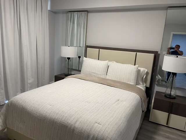 a bedroom with a bed and a lamp on dresser