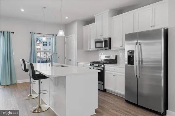 a kitchen with stainless steel appliances a refrigerator a stove a sink a dining table and chairs