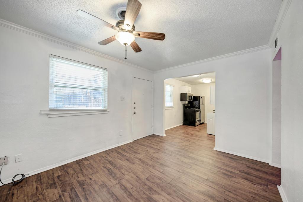 2401 Manor Road, Unit 133 Austin, TX 78722 - Photo 11 of 20 A well-lit living area with rich wood-look flooring flows seamlessly into a compact, efficient kitchen space.
