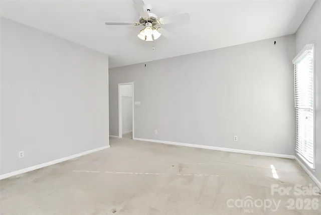 an empty room with a window and a ceiling fan