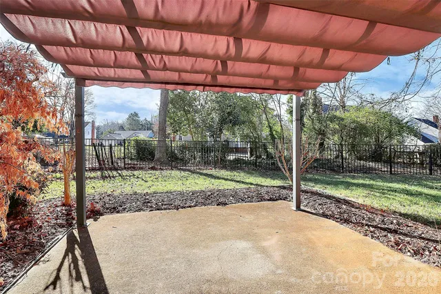 a view of a backyard with wooden fence and a large tree