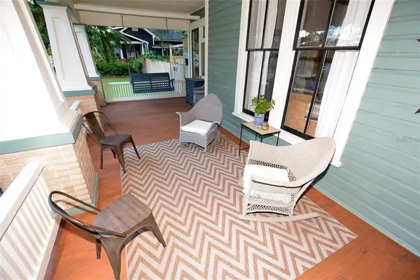 a view of a backyard with table and chairs potted plants and large tree