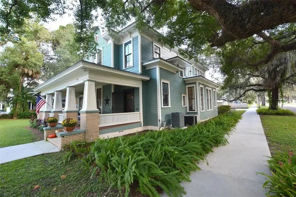 a view of a house with a yard plants and large trees