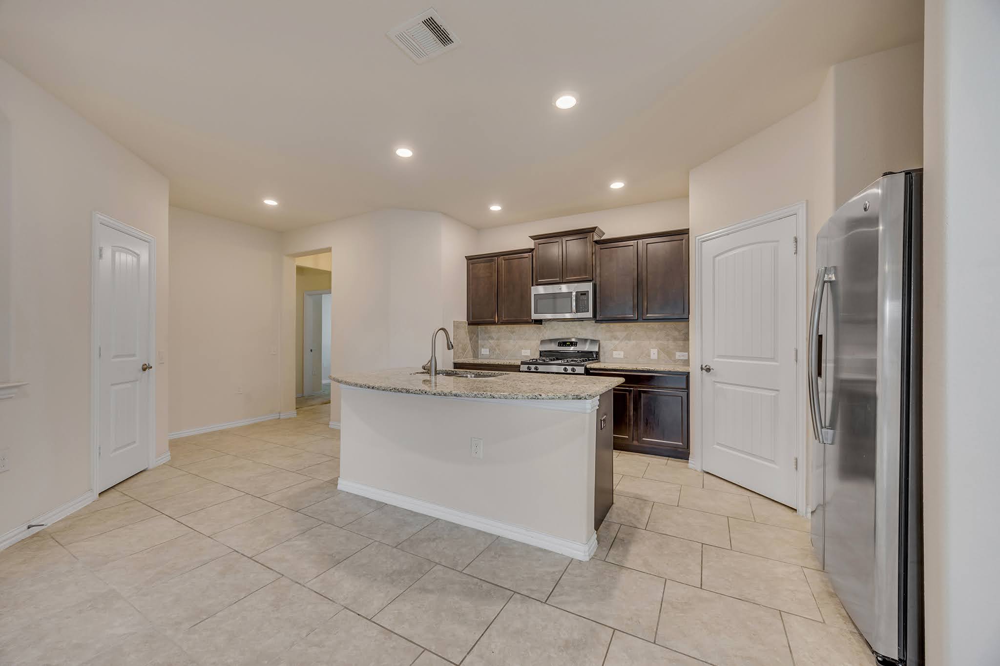 7212 Vail Ridge Street Austin, TX 78744 - Photo 5 of 26 Gleaming stainless steel appliances complement rich cabinetry and granite countertops in this functional kitchen.