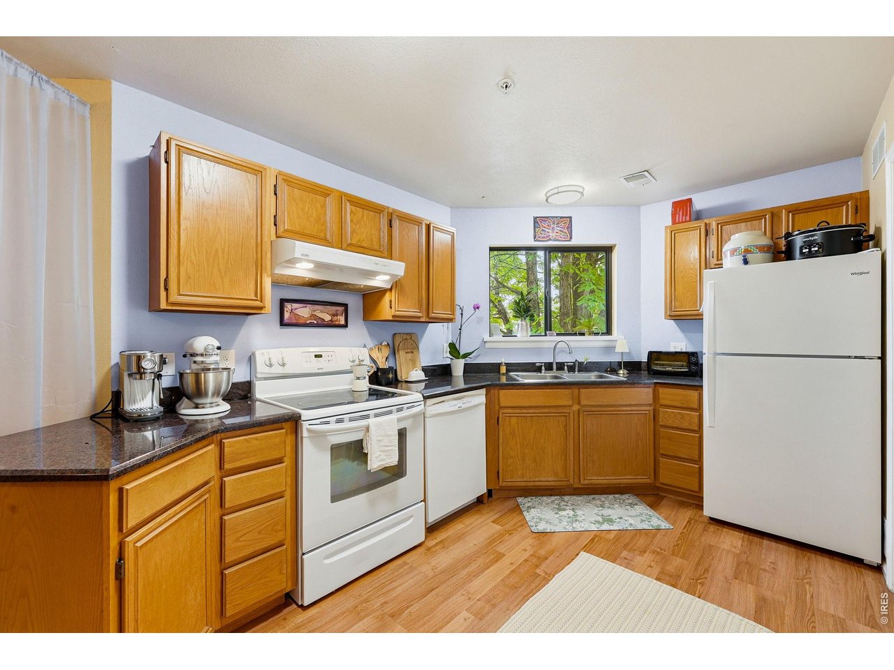 4985 Twin Lakes Road, Unit 94 Boulder, CO 80301 - Photo 6 of 29 The efficient kitchen features ample cabinet space and a view from the window over the sink to a mature green, leafy tree.