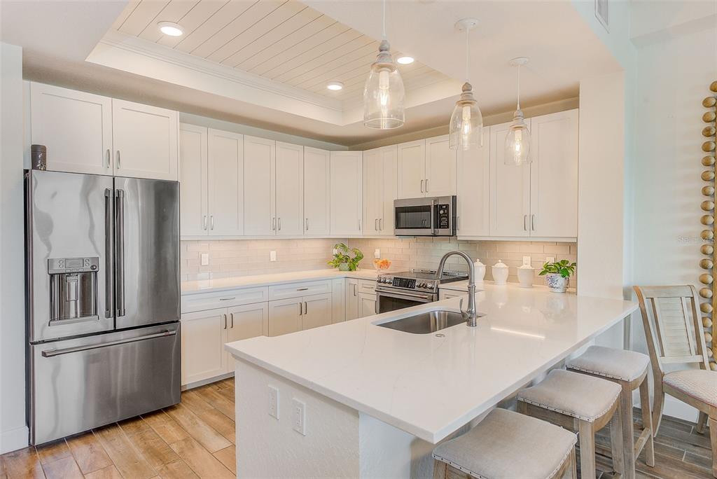 20001 Gulf Boulevard, Unit 403 Indian Shores, FL 33785 - Photo 9 of 43 a kitchen with white cabinets and stainless steel appliances