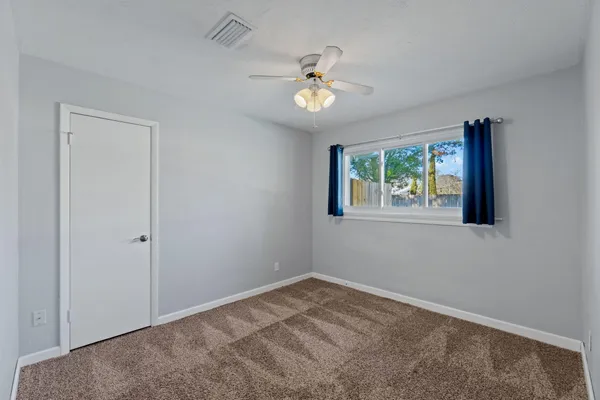 a view of an empty room with a chandelier fan