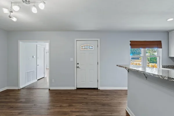 a view of an empty room with wooden floor and a fan