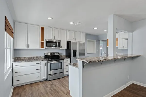 a kitchen with granite countertop white cabinets and stainless steel appliances