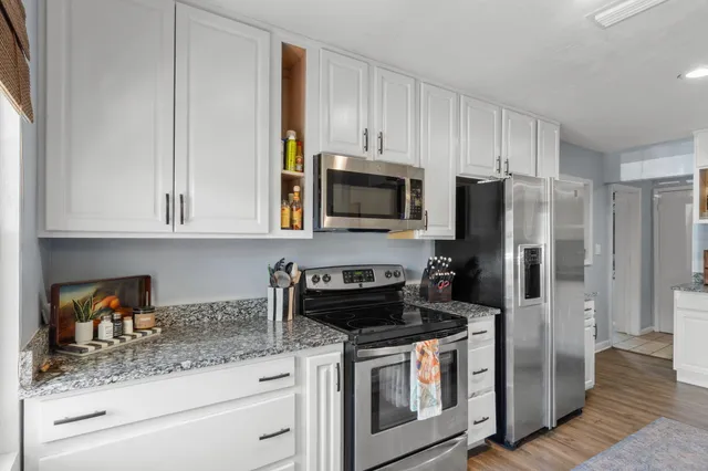 a kitchen with stainless steel appliances granite countertop white cabinets a refrigerator and a stove
