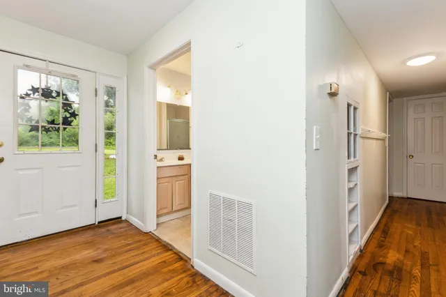 a view of a hallway with wooden floor and a bathroom