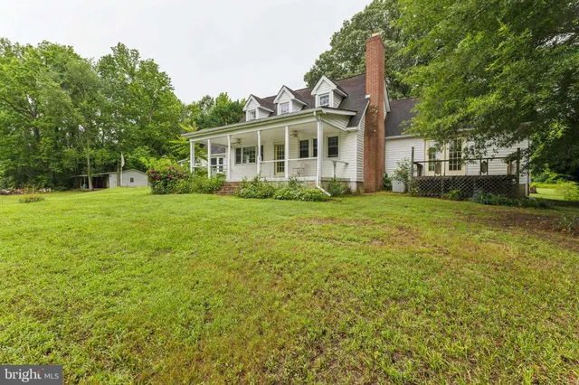 a view of a house next to a big yard and large trees