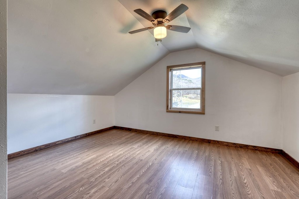 734 Bell Creek Road Hiawassee, GA 30546 - Photo 11 of 30 an empty room with wooden floor ceiling fan and window