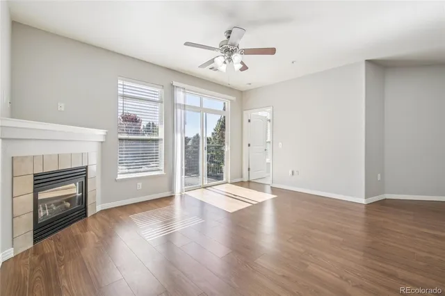 an empty room with wooden floor fireplace and windows