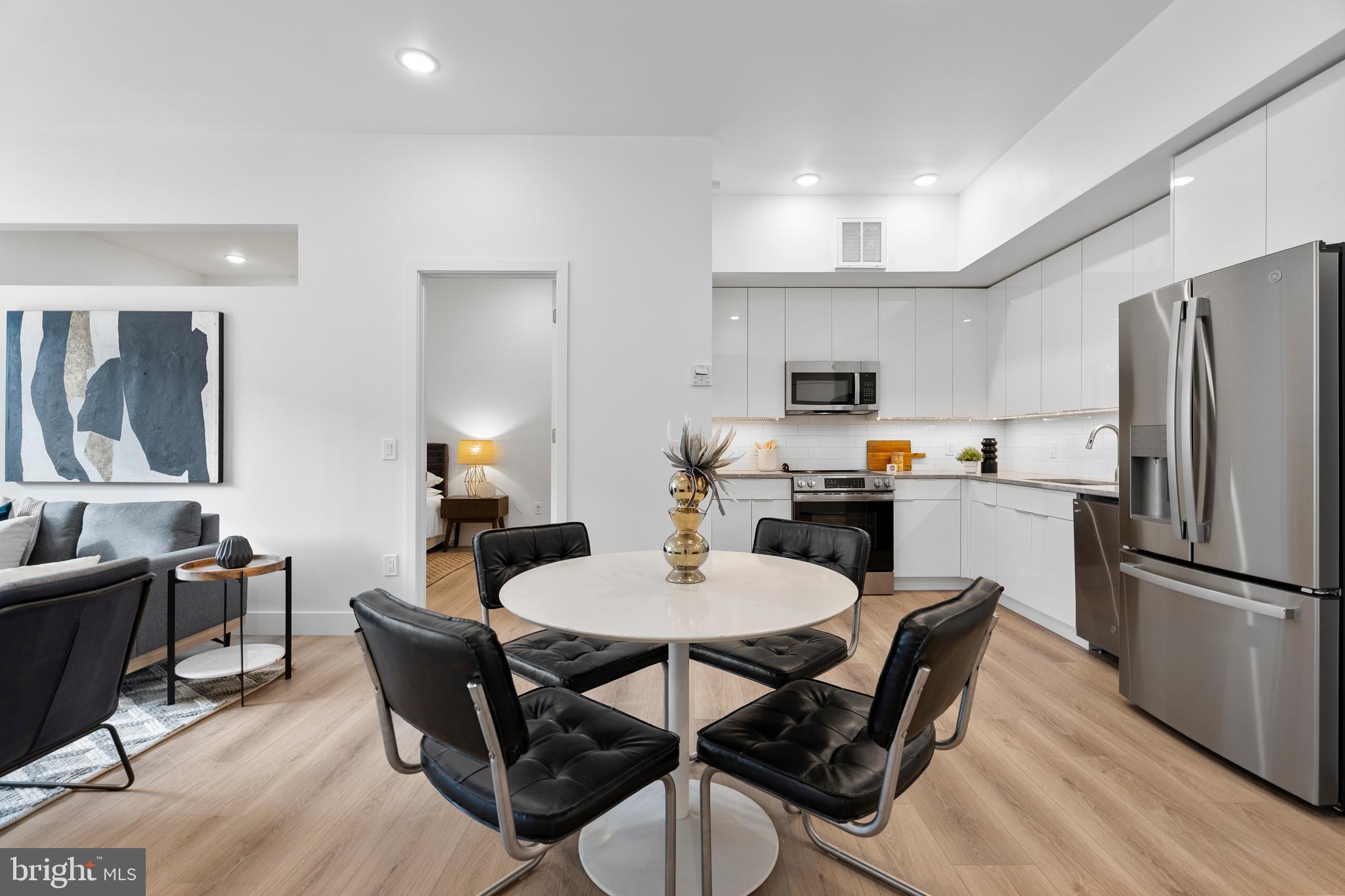 300 Christian Street, Unit 202 Philadelphia, PA 19147 - Photo 6 of 27 a kitchen with stainless steel appliances granite countertop a dining table chairs refrigerator and a sink