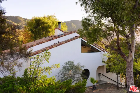 a view of a house with a yard and a large tree