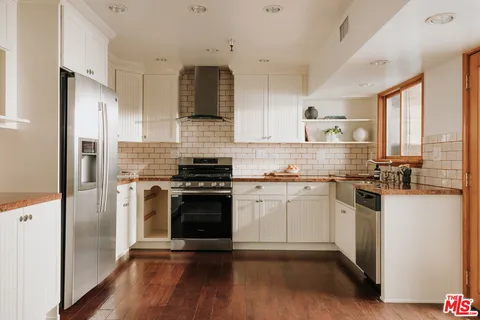 a kitchen with stainless steel appliances a sink cabinets and a wooden floor