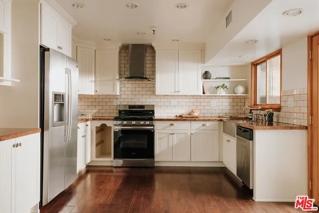 a kitchen with stainless steel appliances a sink cabinets and a wooden floor