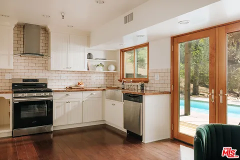 a kitchen with granite countertop a stove a sink and a refrigerator