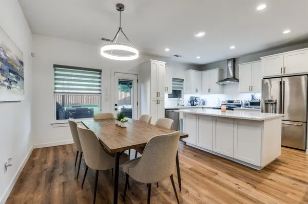 a kitchen with stainless steel appliances granite countertop a dining table chairs stove refrigerator and cabinets