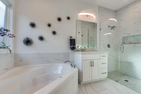 a bathroom with a tub sink mirror and shower