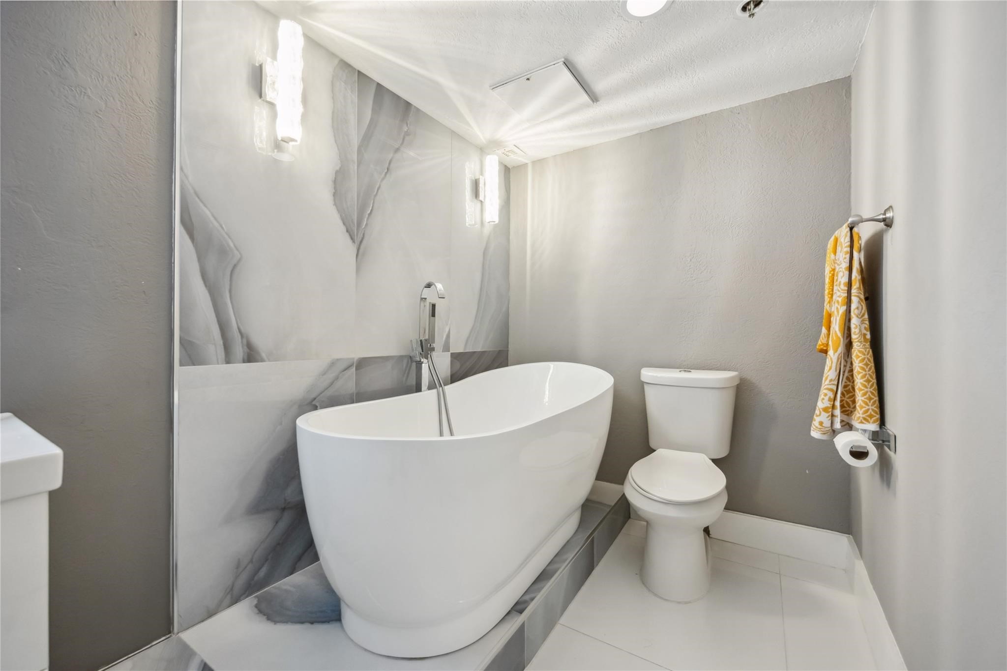 3525 Sage Road, Unit 1713 Houston, TX 77056 - Photo 17 of 25 This modern bathroom features a sleek freestanding bathtub, elegant marble-patterned walls, and contemporary lighting.