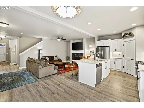 a large living room with stainless steel appliances kitchen island granite countertop a large kitchen island a stove a sink a refrigerator and cabinets
