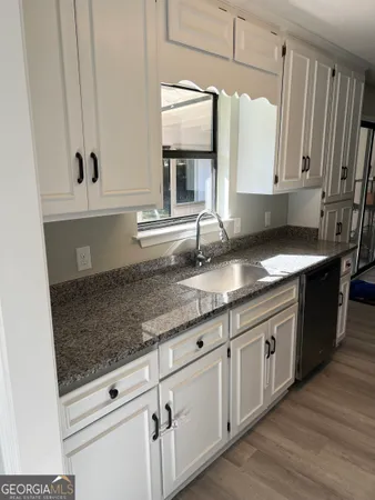 a kitchen with granite countertop white cabinets and sink